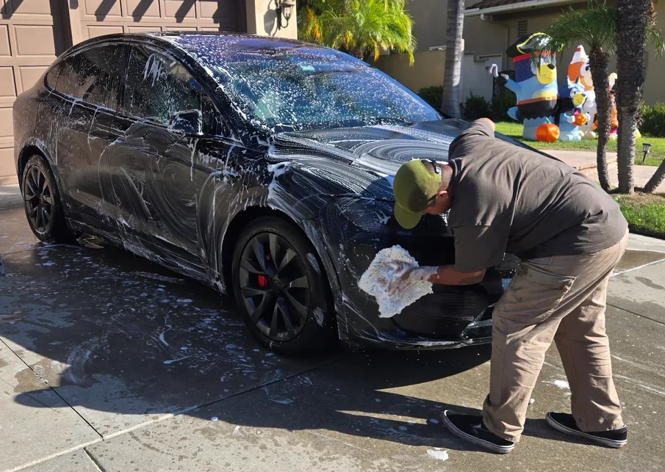 David hand washing a black Tesla during a mobile detailing appointment.